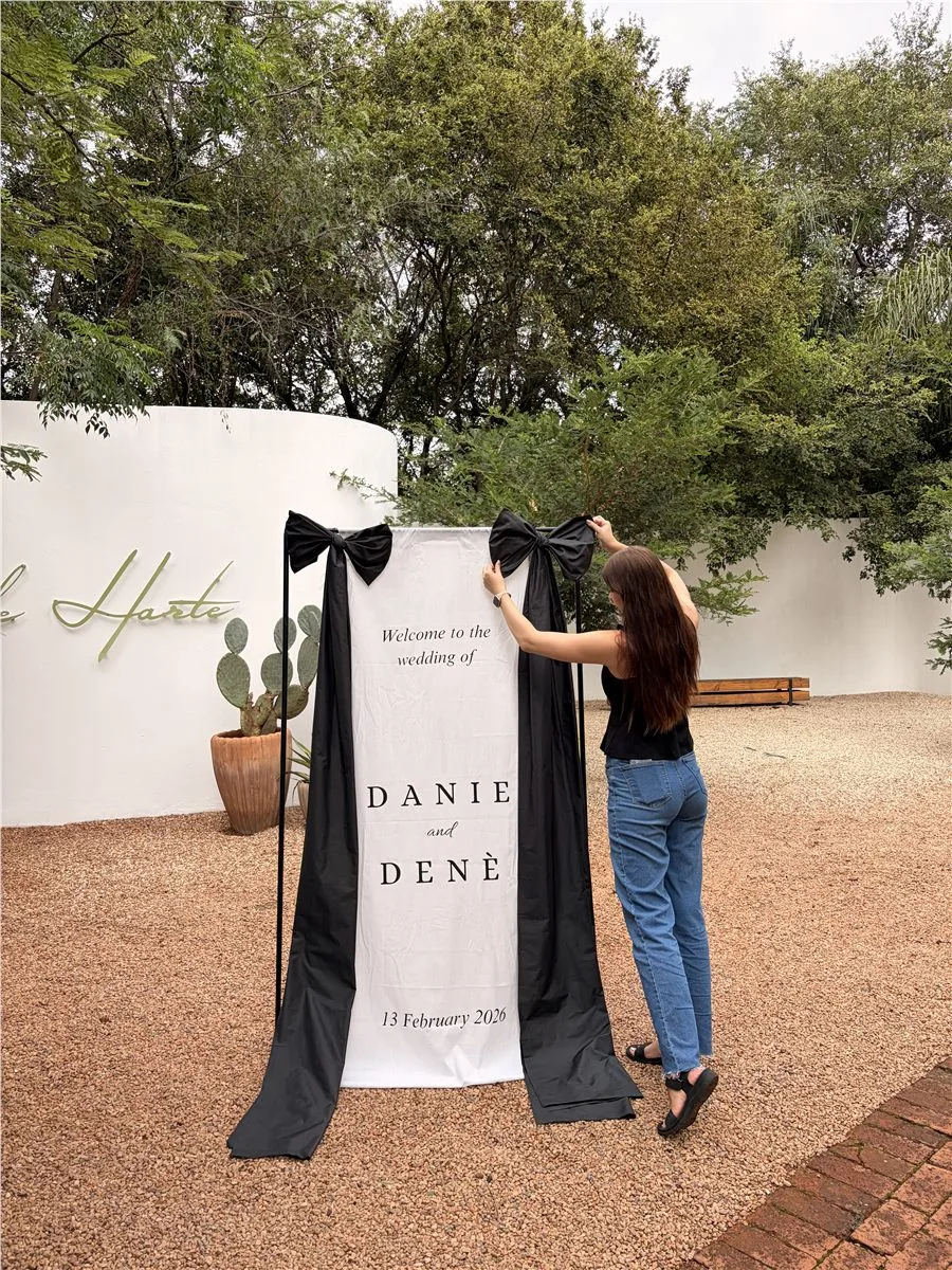 Fabric welcome banner with black bows being hung at a venue entrance