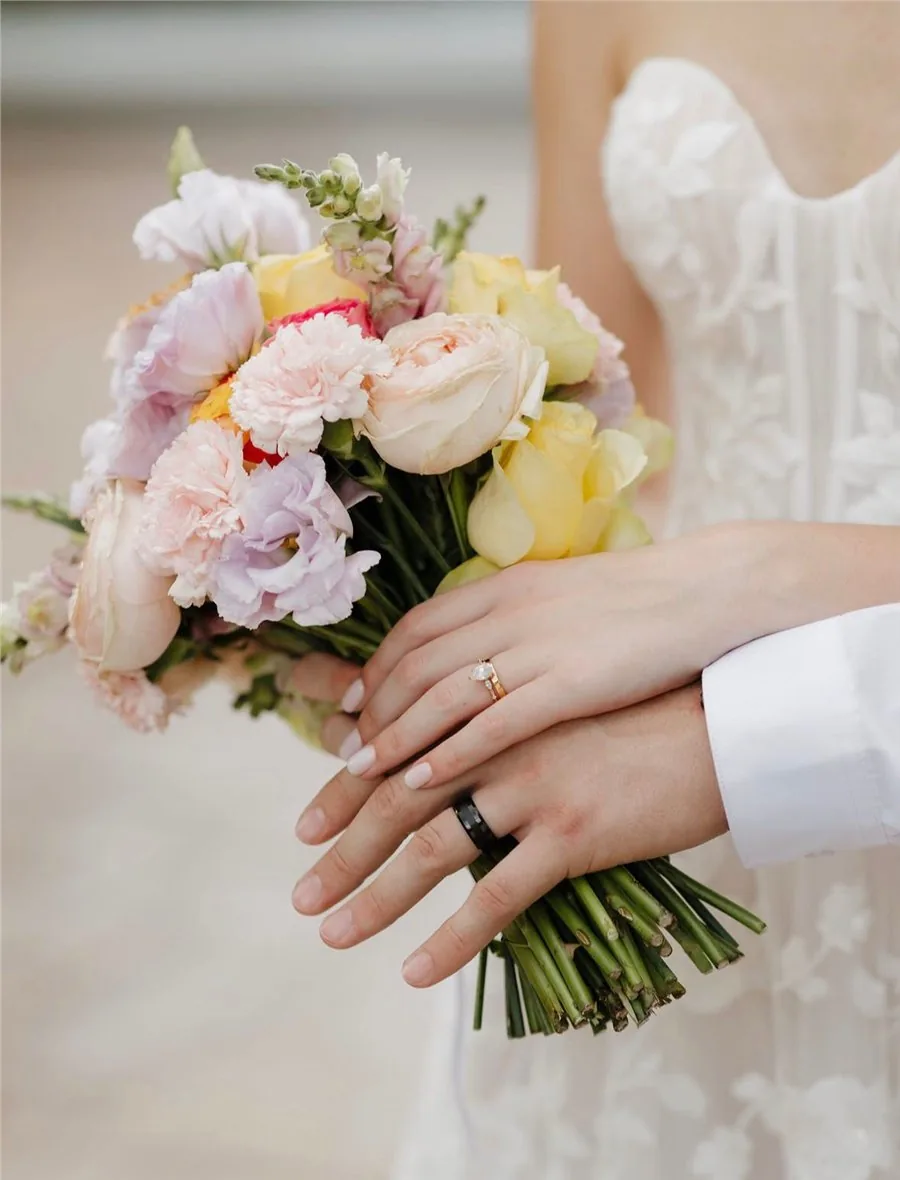 Bride and groom holding a pastel bridal bouquet of roses, carnations and lisianthus