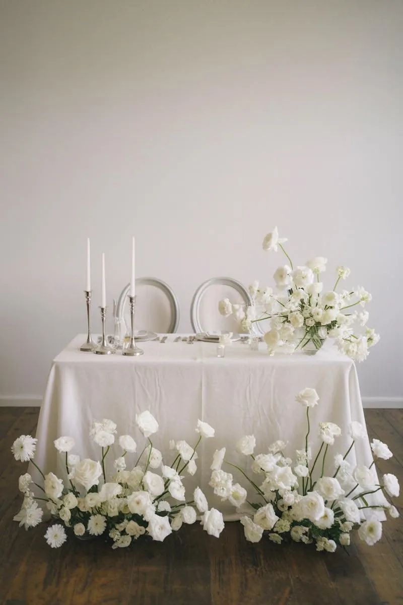 Bridal table styled with white florals along the base and silver taper candles