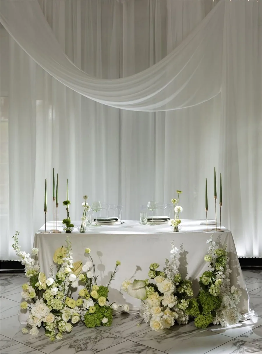 Sheer white draped backdrop and swagged canopy above a bridal table