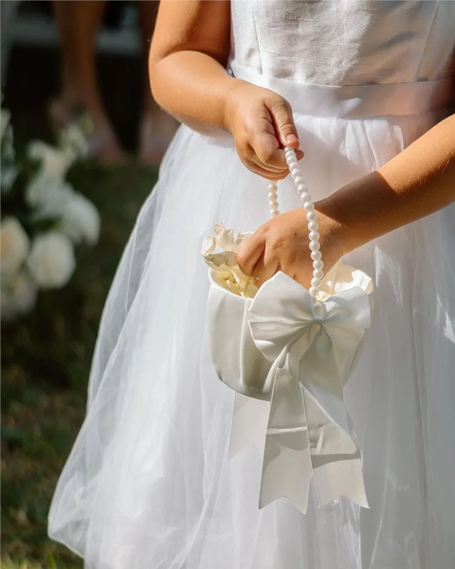 Flower girl holding a satin confetti basket of petals
