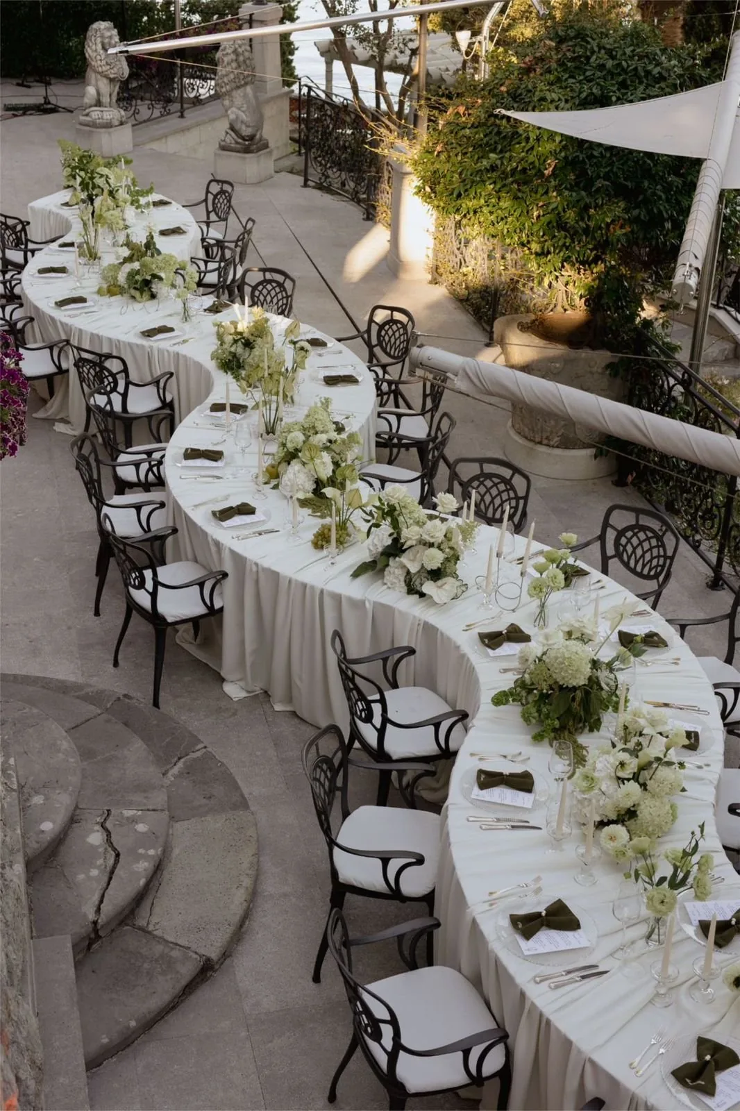 Curved reception table dressed with white florals and taper candles